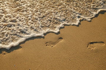 Footprints of bare feet on the sea beach sand.