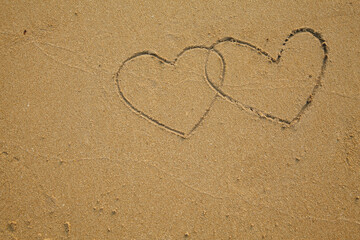 Fototapeta na wymiar Two hearts is drawn on the sea beach sand.