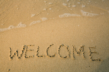Fototapeta na wymiar Welcome - handwritten on the soft beach sand.