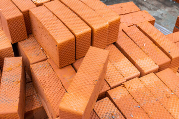 burnt bricks of orange color with corrugated sides lie on a pallet