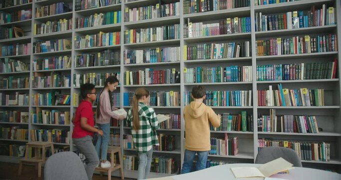 Schoolchildren take books from shelves to read in library