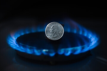 A gas burner and quarter of a dollar coin, money on a home gas stove. The cost of natural gas....