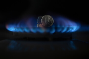 A gas burner and a Russian ruble coin, money on a home gas stove. The cost of natural gas. Price...