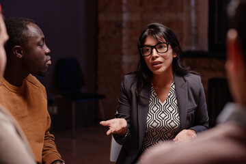 Horizontal shot of modern psychologist working with group of people having same problems speaking about something