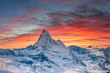 Fototapeta na wymiar Scenic view of snowcapped matterhorn mountain against cloudy sky. Beautiful famous snow covered landscape during sunset. Magnificent white valley in alps during winter.