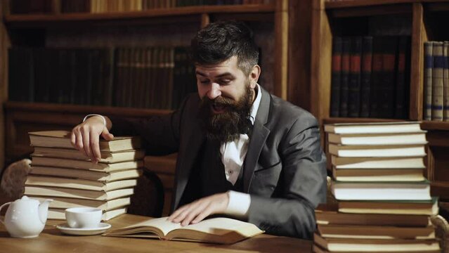 Bearded man in library with books on background. Middle age man reading books at home library. Professor.
