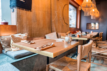 Fototapeta na wymiar Table and chairs arranged in illuminated restaurant. Empty rustic style dining area in hotel. Interior of stylish eating place at luxurious ski resort.