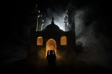 Silhouette of mosque building on toned foggy background. Ramadan Kareem background. Mosque at sunset. Praying people