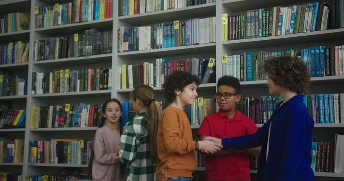 Boy with kinky hair runs to friend to choose book in library