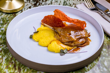 Duck leg confit on grey plate side view