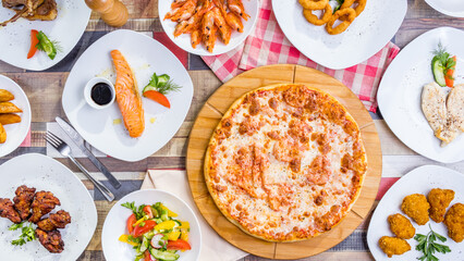 Italian pizza Margherita, salmon steak, shrimps, vegetable salad, chicken wings, grilled chicken breast and onion rings top view food