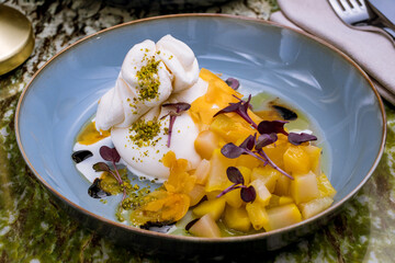 Salad with buratta cheese on grey plate on green marble table