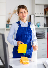 adult female cleaner with cleaning supplies washing in cabinet