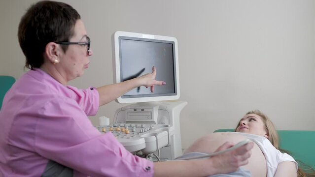 The doctor uses ultrasound equipment when examining a pregnant woman. A professional female obstetrician-gynecologist conducts a prenatal examination of the expectant mother in a hospital