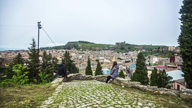 Static view of a couple watching the scenic town of Chiesa Maria SS del Malpasso, Sicily, Italy on a cloudy evening in timelapse.