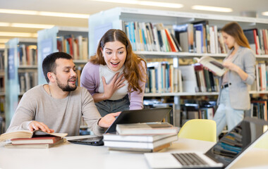 Positive young adults communicating while preparing to exam in library