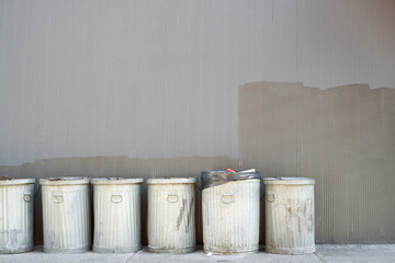 Metal trash cans lined up in a row on a New York City sidewalk.