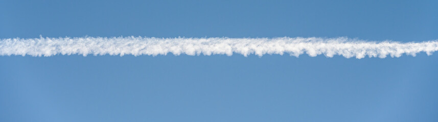 Bright white contrail cloud against a clear blue sky, as a graphic background
