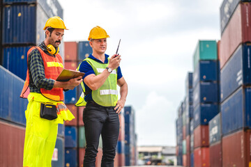 Professional engineer container cargo foreman team in helmets working standing and using walkie...