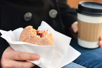 Woman Holding a Jelly Donut and Coffee