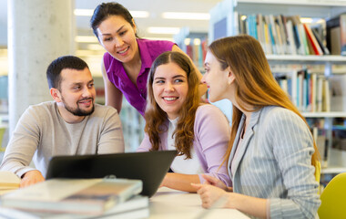Friendly happy group of students preparing together for exam in modern university library