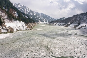 Fototapeta na wymiar Toyama,Japan - April 23, 2022: A partially ice-covered Kurobe lake and Kurobe Dam in spring 