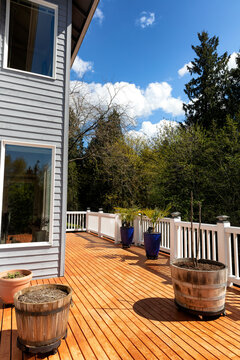 Home outdoor wood deck just freshly stained during early spring time with trees and sky in background