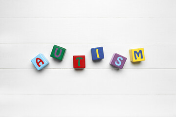 Word AUTISM made of cubes on white wooden background