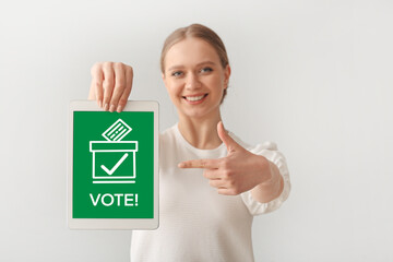 Young woman with tablet computer on light background. Voting online