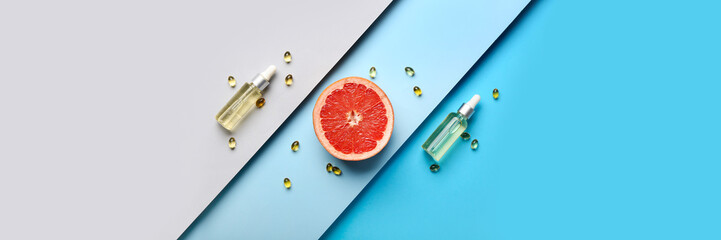 Cosmetic bottles with vitamins and grapefruit slice on color background. Banner for design - obrazy, fototapety, plakaty