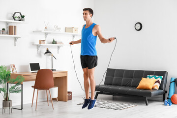 Sporty young man jumping rope at home