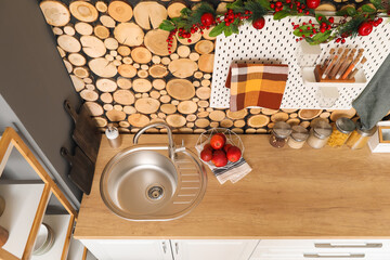 Counter with silver sink, pegboard, jars and basket of apples near wooden wall in kitchen