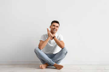 Young barefooted man sitting near light wall - Powered by Adobe
