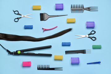 Composition with hair strand, hairdresser's tools and curlers on blue background