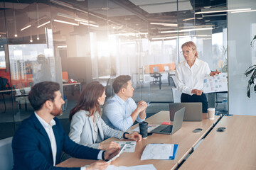 Naklejka premium Businessman Gives Report to His Business Colleagues, Pointing at the Results Showing Statistics.