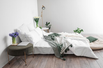 Interior of light bedroom with flowers in vases and houseplants