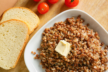 Plate of tasty buckwheat porridge, bread and tomatoes, closeup