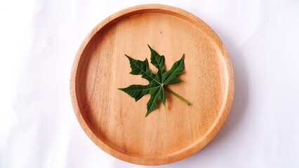 green papaya leaf on wooden plate. top view. Papaya leaves contain over 50 ingredients