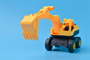 Construction plastic backhoe tractor toy isolated on a blue background