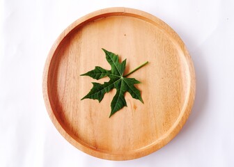 green papaya leaf on wooden plate. top view. Papaya leaves contain over 50 ingredients