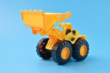 Obraz na płótnie Canvas Construction plastic backhoe tractor toy isolated on a blue background