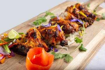 A view of a wood board of tandoori chicken.