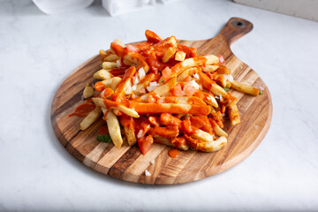 A view of an entree of loaded french fries, topped with hot sauce.