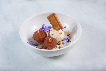 A view of a bowl of gulab jamun, with ice cream and a cookie.