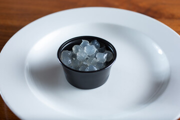 A closeup view of a condiment cup filled with crystal boba.