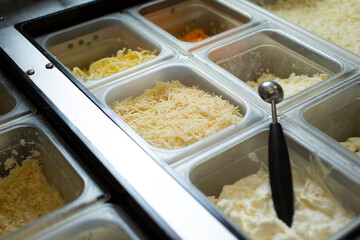 A view of a station full of pizza toppings and ingredients, seen at a local pizzeria.