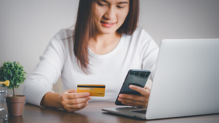 Woman shopping online with credit card shown on the back of the card and using smartphone for online shopping, Online payment concept.