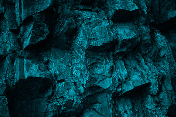 Blue green rock texture. Toned the rough surface of the mountain. Close-up. 3d shape. Dark teal stone background with space for design. Wallpaper. Volumetric granite. Grunge.