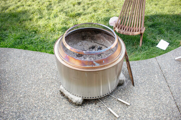 A view of a stainless steel fire pit, in a backyard setting.