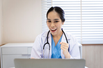 An Asian female doctor in Thailand is communicating with patients over the Internet with her...